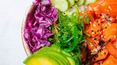 Nahaufnahme einer Poke Bowl mit Lachs, Avocado, Rotkohl, Gurken und Seetang vom Foodservice