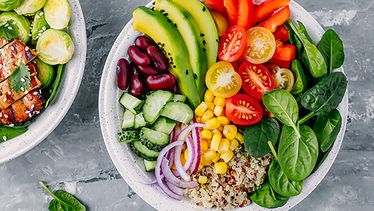 Frische Salatbowl von einem Foodservice mit Avocado, Tomaten, Gurken, Paprika, Spinat, Mais, Bohnen und Zwiebeln